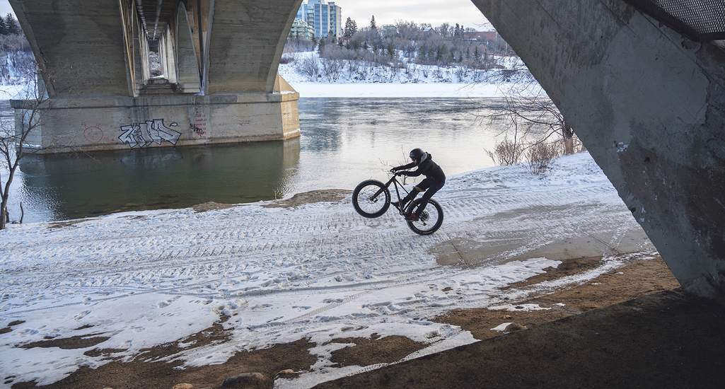 Winter biking under the Broadway Bridge along the shores of the South Saskatchewan River in the city of Saskatoon