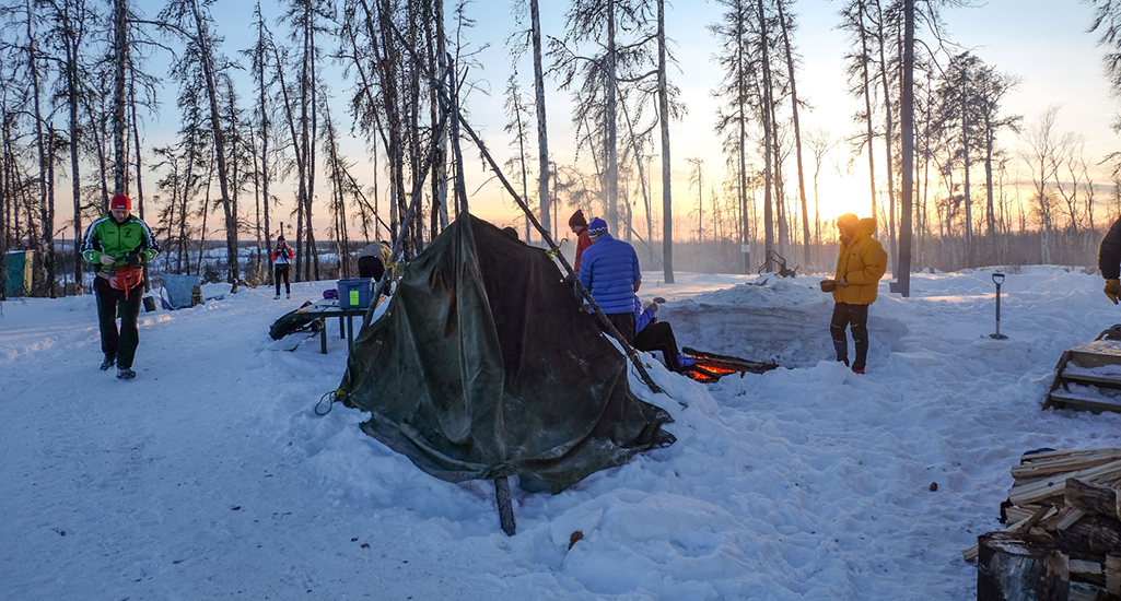 A group of participants set up a winter camp as the sun sets at the Don Allen Saskaloppet near La Ronge Saskatchewan
