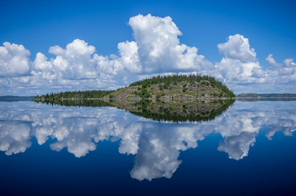 A perfect reflection of an island on a sunny morning on Tazin Lake, Saskatchewan